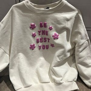 White sweatshirt with pink letter saying “be the best you”